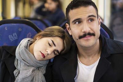 Young woman leaning head on man's shoulder in tram