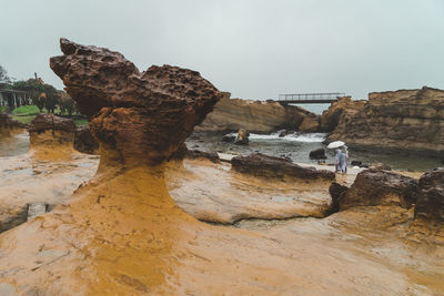 Rock formations on shore against sky