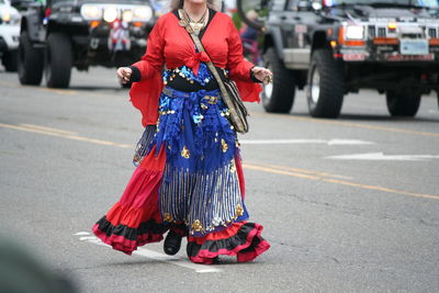 Midsection of woman with umbrella on road