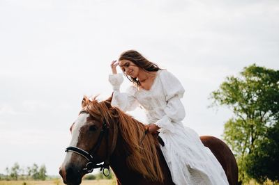 Young woman riding horse on field