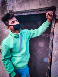 Young man wearing pollution mask while standing against wall