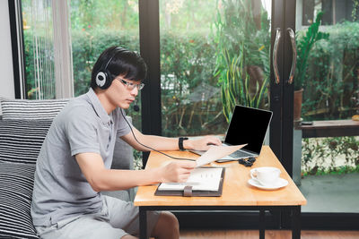 Young woman using mobile phone while sitting on table