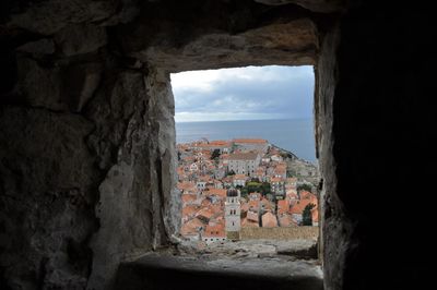 Buildings against sky seen through window