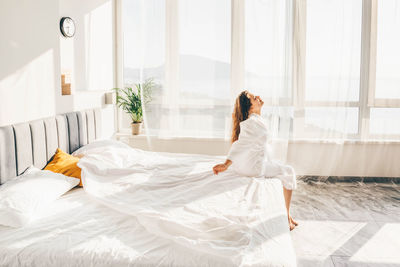 Woman sitting on bed at morning