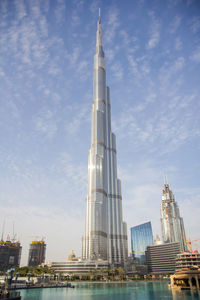 Low angle view of skyscrapers against cloudy sky