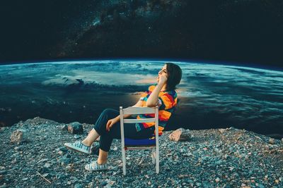 Woman sitting on rock by sea