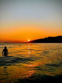 Silhouette people on beach against sky during sunset