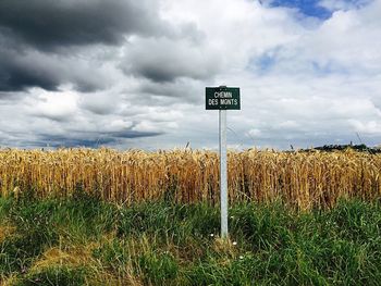 View of field against cloudy sky