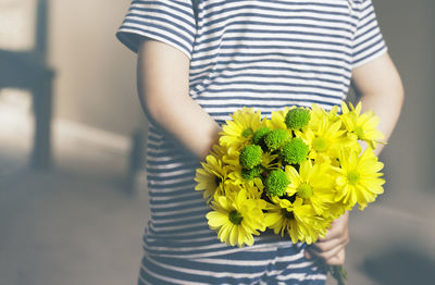 Midsection of woman holding yellow flower