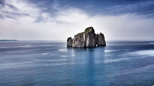 Scenic view of rock formation in sea against sky