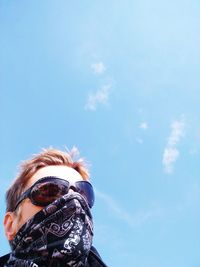 Low angle view of man wearing eyeglasses and scarf against sky