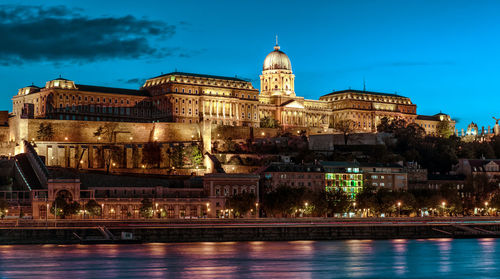 Illuminated royal palace of buda against sky at dusk