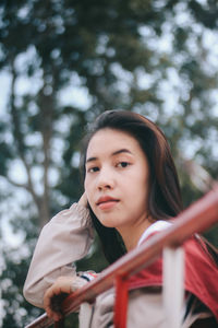 Portrait of beautiful young woman against trees