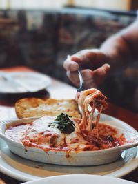 Close-up of person eating lasagna