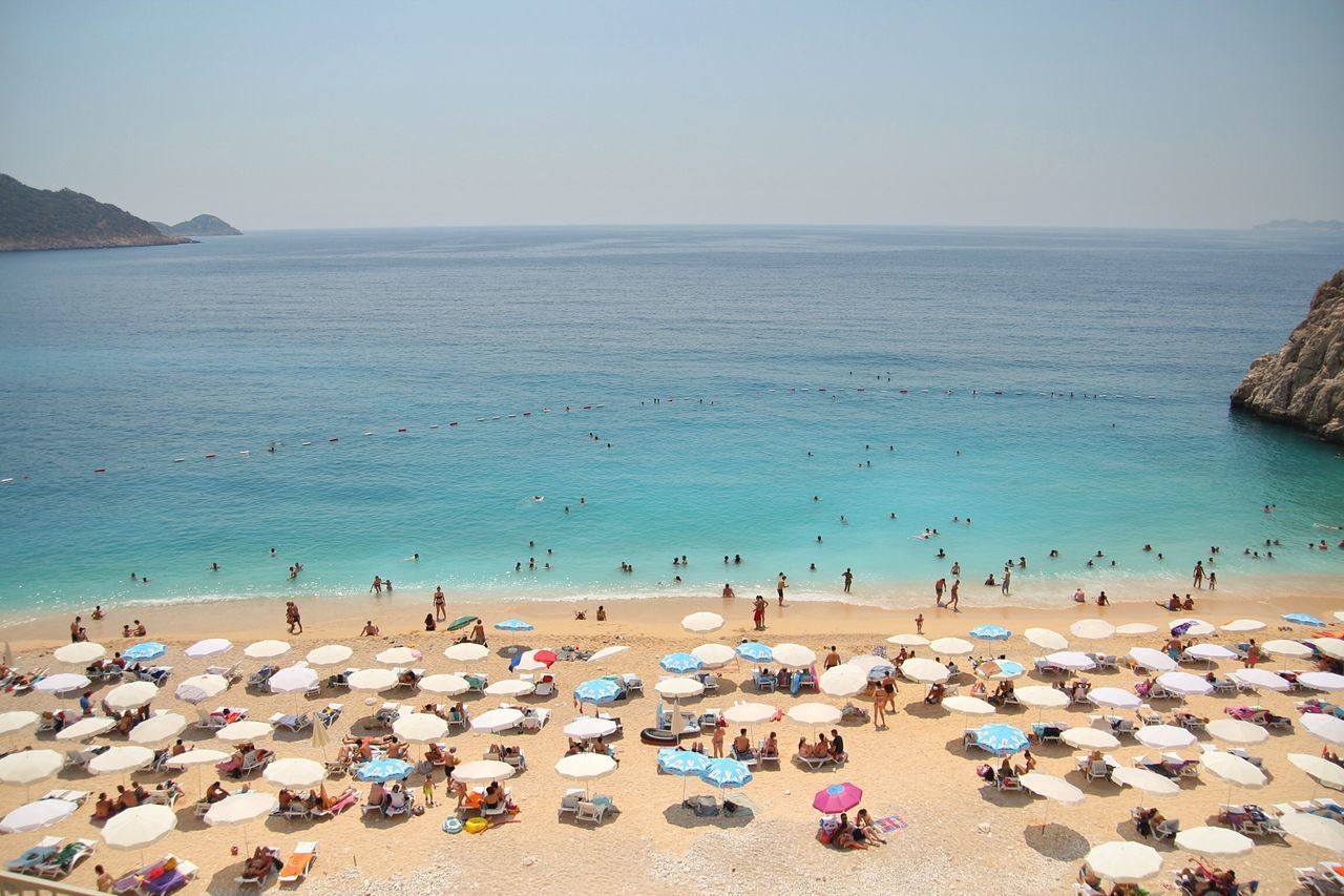 sea, beach, water, large group of people, horizon over water, shore, vacations, sand, person, leisure activity, lifestyles, relaxation, men, mixed age range, summer, clear sky, scenics, beach umbrella, tranquil scene