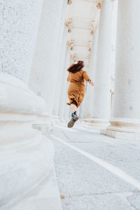Rear view of woman running between column