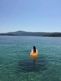 Woman on boat in sea against clear sky