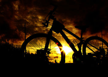 Silhouette bicycle on field against sky during sunset