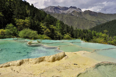 Scenic view of hot spring by trees at mountains