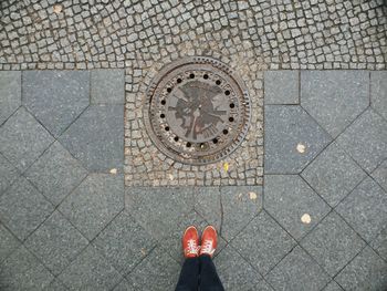 Low section of person by manhole on footpath