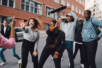 Happy multi-ethnic friends dancing on road in city