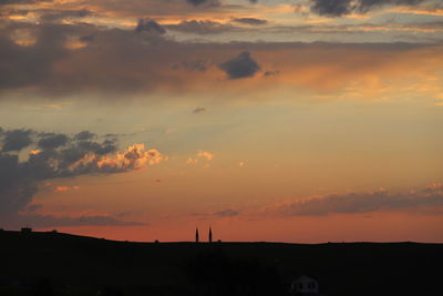 Silhouette buildings against dramatic sky during sunset