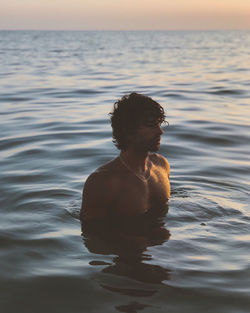 Man swimming in sea during sunset