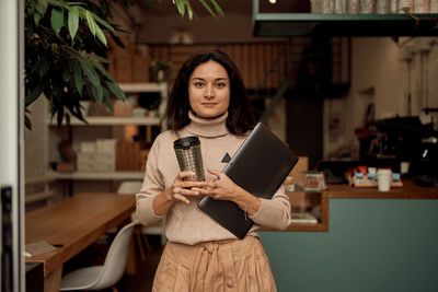 Portrait of smiling woman standing in cafe