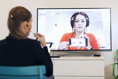 Rear view of businesswoman attending conference call in creative office