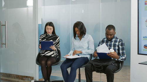 Woman and man sitting against glass wall