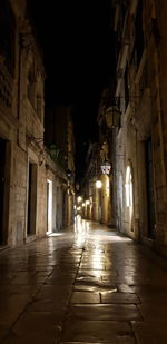 Empty alley amidst buildings in city at night