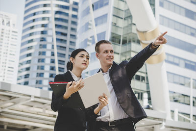 Low angle view of business people discussing while standing against building