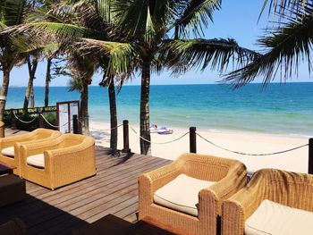 Chairs and table by sea against clear sky