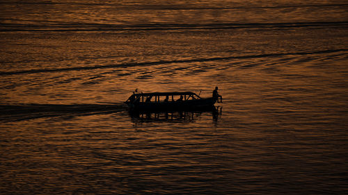 Silhouette person in boat on sea against sky during sunset