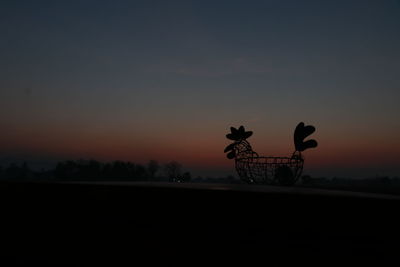 Silhouette bicycle on field against sky during sunset