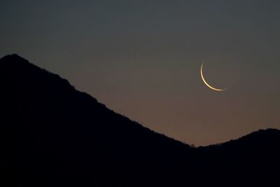 Low angle view of silhouette mountain against sky at night