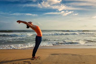 Full length of woman standing at beach against sky