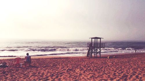 Rear view of man on beach against clear sky