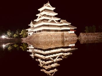 Temple by building against sky at night