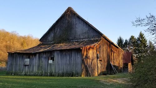 Abandoned barn on field against clear sky