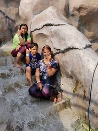 Portrait of friends sitting on rock