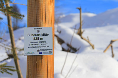 Close-up of information sign on wooden post