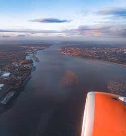 Aerial view of city by sea against sky