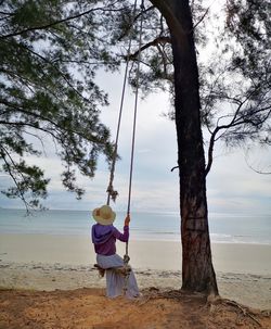 Rear view of women standing on beach against sky