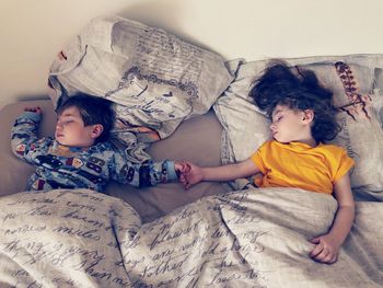 Cute siblings sleeping on bed at home