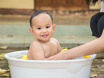 Portrait of shirtless baby boy sitting in tub
