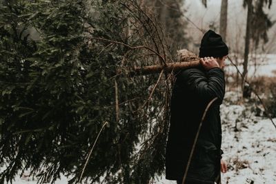 Rear view of woman standing on snow covered forest