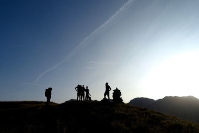 Low angle view of silhouette people standing on mountain against sky