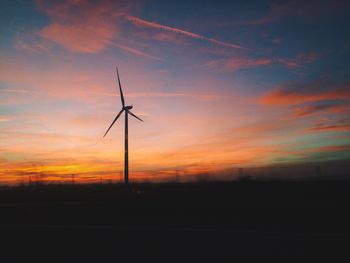 Wind turbine on silhouette landscape against dusk