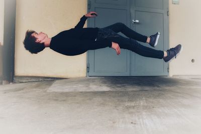 Side view of young man levitating at home